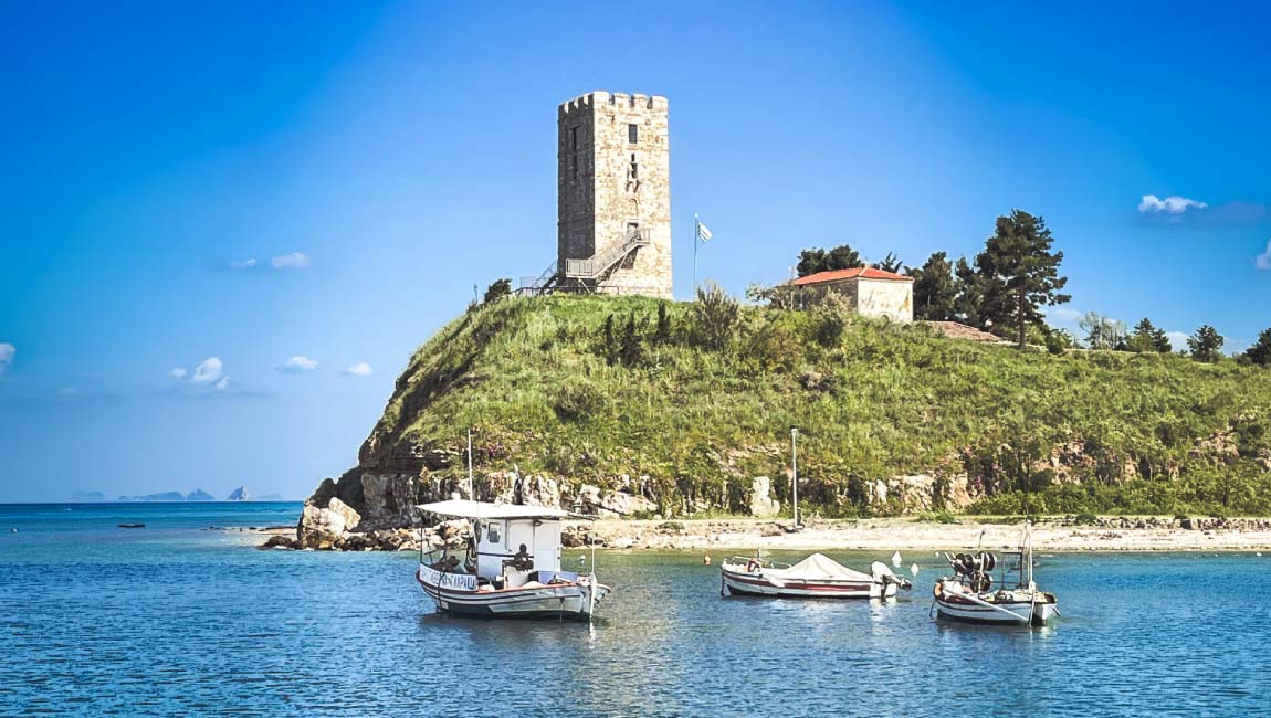 Byzantine tower in Nea Fokaia, Halkidiki with fishing boats in the harbour