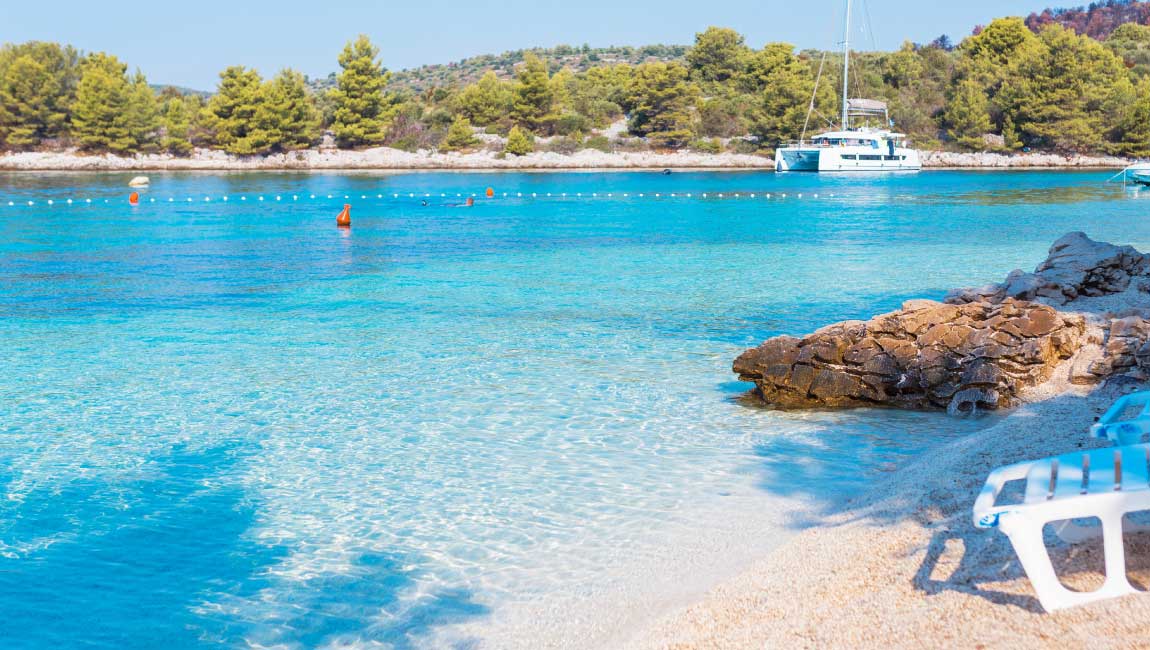 Small beach with turquoise waters and a sailing boat in Loutra Agia Paraskevi, Halkidiki
